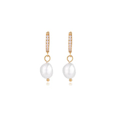 Gold huggie hoop earrings with pavé crystals and white freshwater pearl drops on cream background