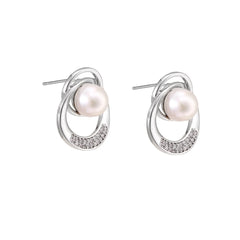 White gold-plated brass earrings with circular design, freshwater pearl center, and diamond accents